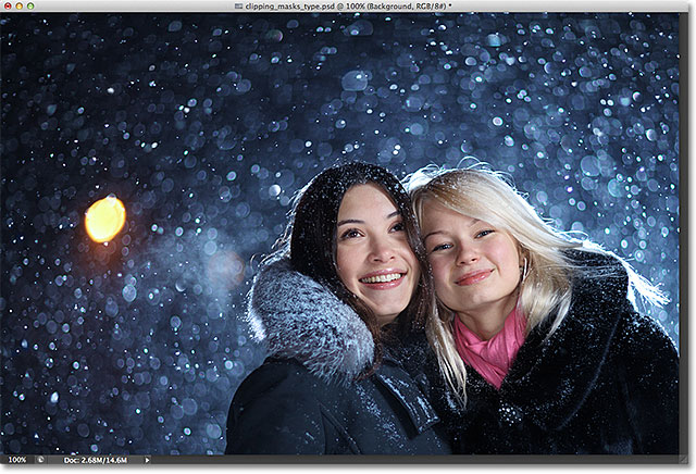 Dua senang teman-teman perempuan muda menikmati salju pada musim dingin malam Natal di atas latar belakang salju. Gambar berlisensi dari Shutterstock oleh Photoshop Essentials.com