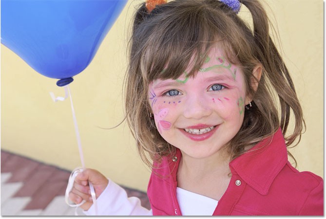 Una chica joven que sostiene un globo azul. Imagen © 2010 Photoshop Essentials.com