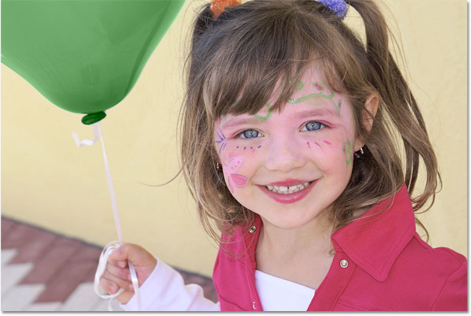 La jeune fille est maintenant tient un ballon vert. Image © 2010 Photoshop Essentials.com