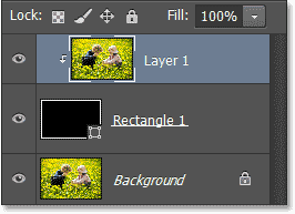 Панель Слои показ Layer 1 прикреплять к форме слоя. Image © 2013 Photoshop Essentials.com