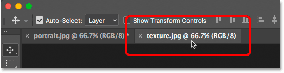 Switching between open images in Photoshop by clicking the document tabs.