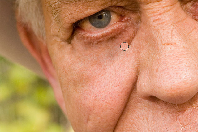 Continuing to remove the larger wrinkle under the man's eye with the Healing Brush. Image © 2016 Photoshop Essentials.com