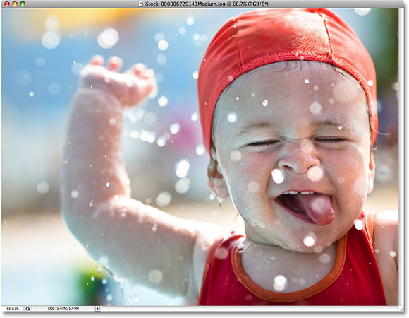 水の中で遊んでいる若い男の子の写真。 フォトショップからライセンスされた画像Essentials.com.