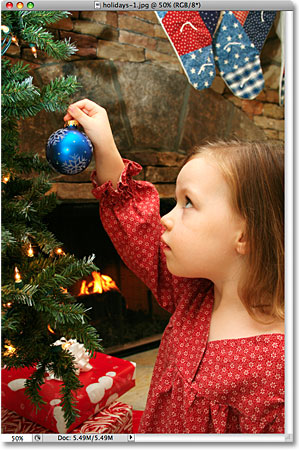 A photo of a girl placing an ornament on a Christmas tree. Image licensed from iStockphoto by Photoshop Essentials.com.